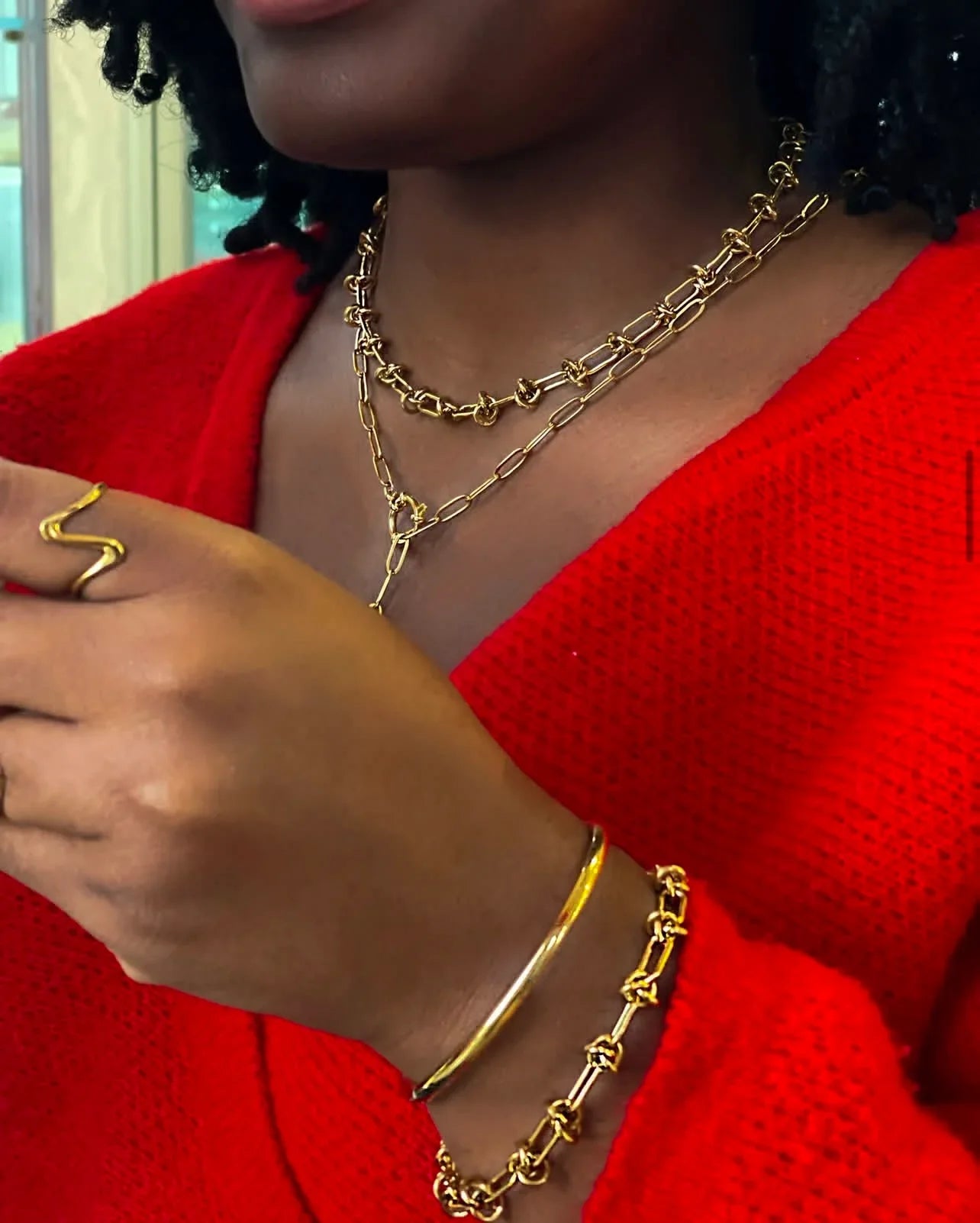 Gioielli artigianali LUEUR in acciaio inossidabile oro su donna con maglione rosso