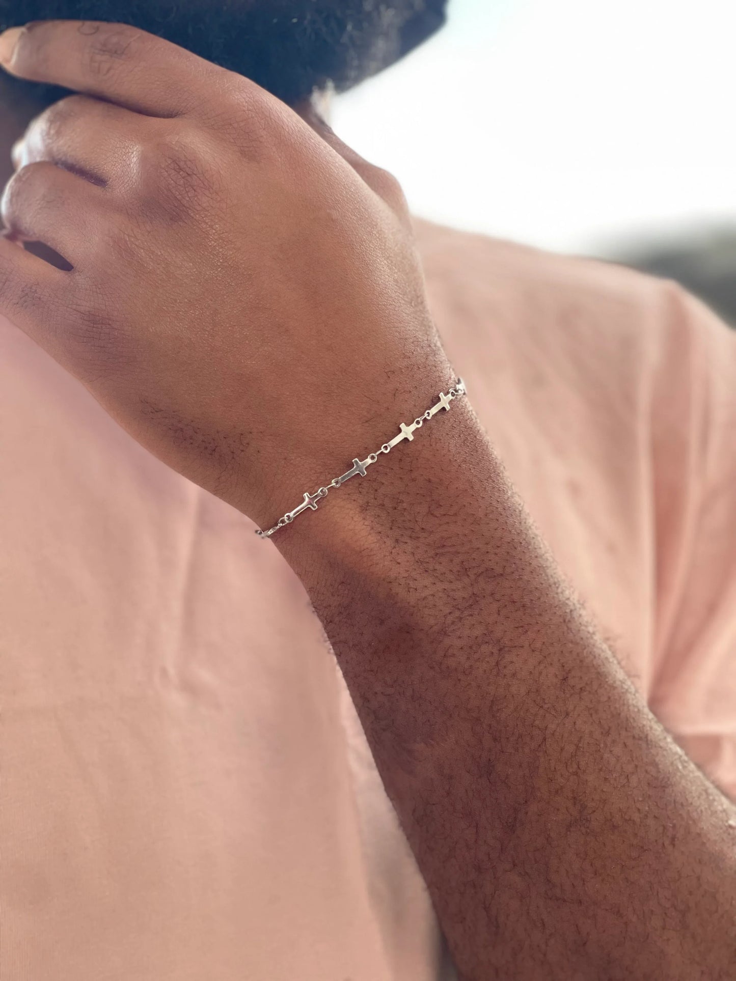 Bracciale artigianale in acciaio inossidabile con croci indossato su fondo rosa, LUEUR gioielli