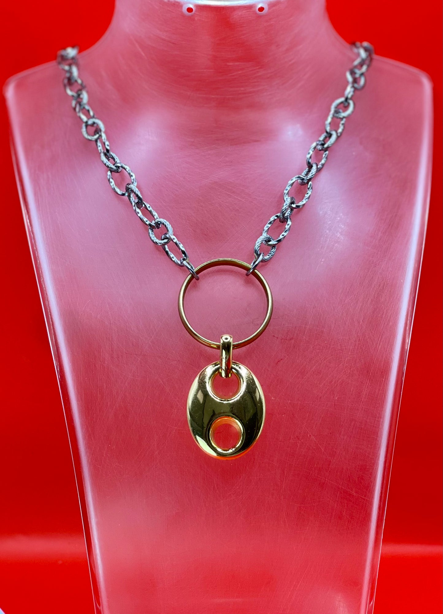 Collana artigianale LUEUR in acciaio inossidabile con ciondolo dorato su busto rosso.